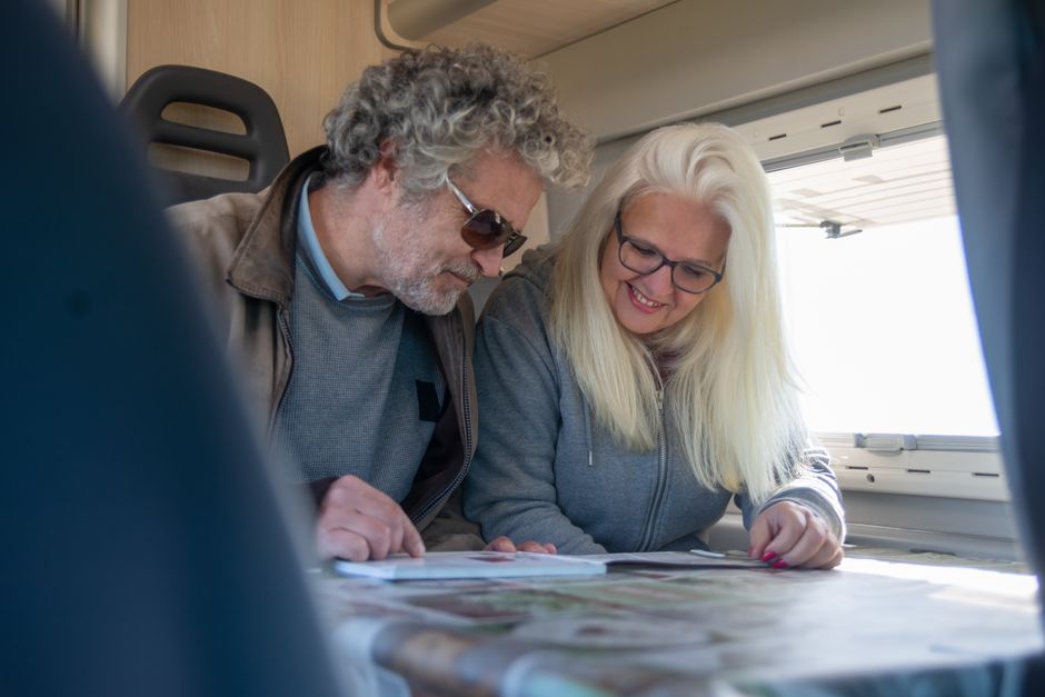 Pareja de personas mayores consultando un folleto de viajes en su domicilio