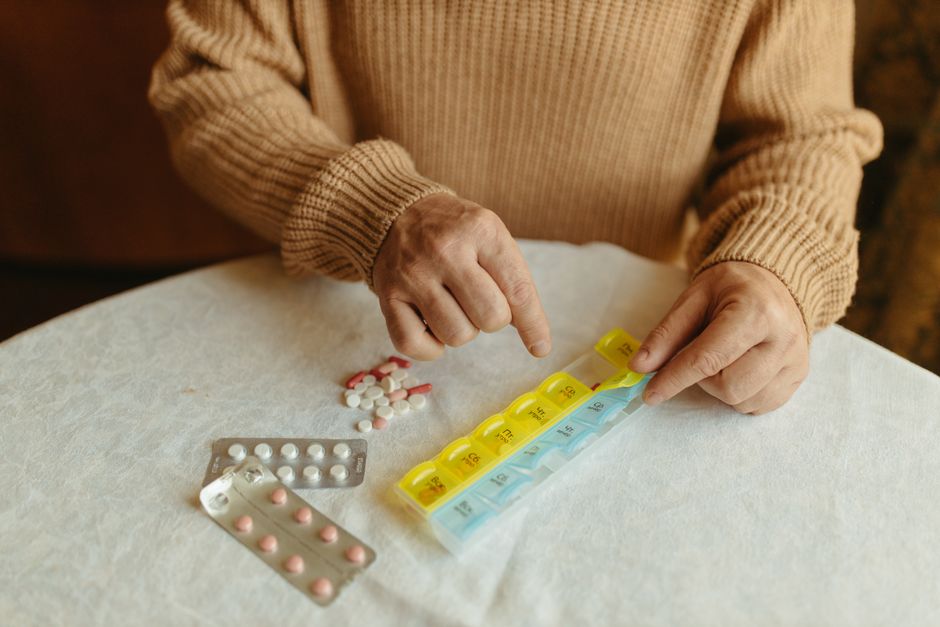 Persona mayor organizando su medicación semanal en un pastillero